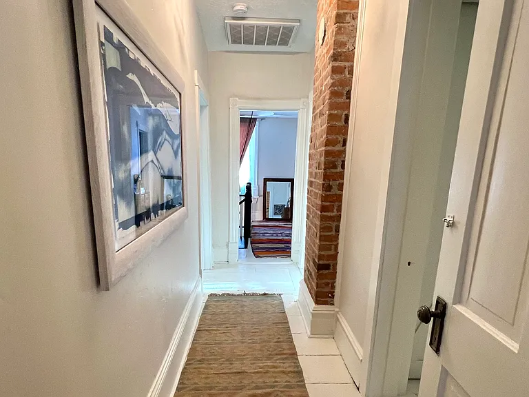 Upstairs hallways with original wood floor and exposed brick - note a wood burning fireplace has been added