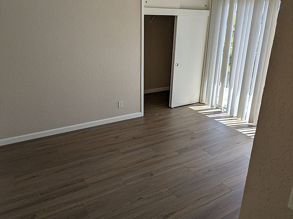 Bedroom with hardwood flooring and large balcony facing the courtyard.