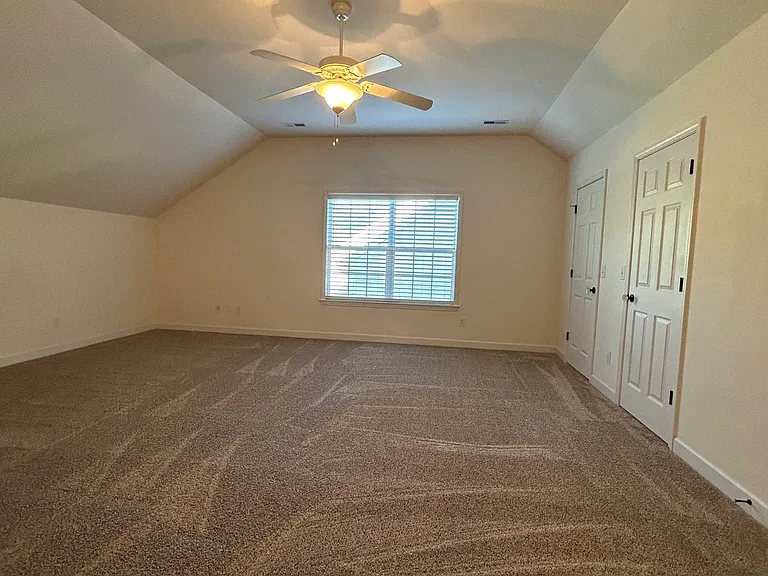 Huge bonus room over two-car garage with newer carpet, ceiling fan, double windows, and double doors to large walk-in closet