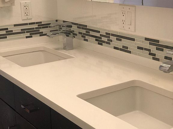 Renovated bathroom with dual sinks and white granite countertops