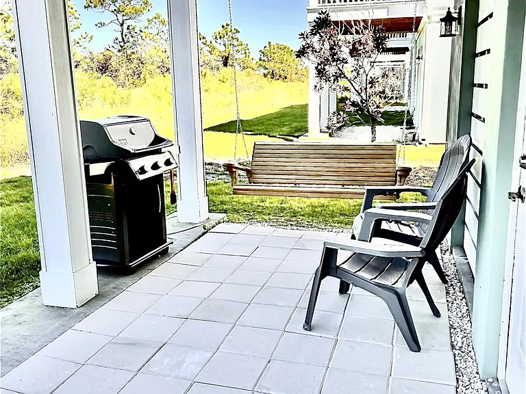 Lower level back patio featuring wood swing and Weber grill.