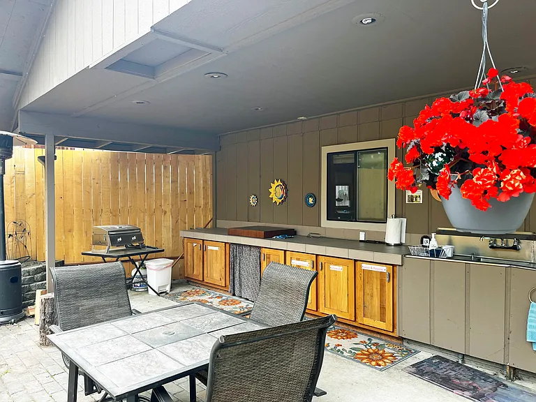 private backyard covered patio with stovetop, pots and pans, large sink, table and chairs