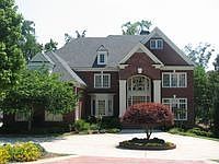 Four sided brick home with circular driveway and three car garage.