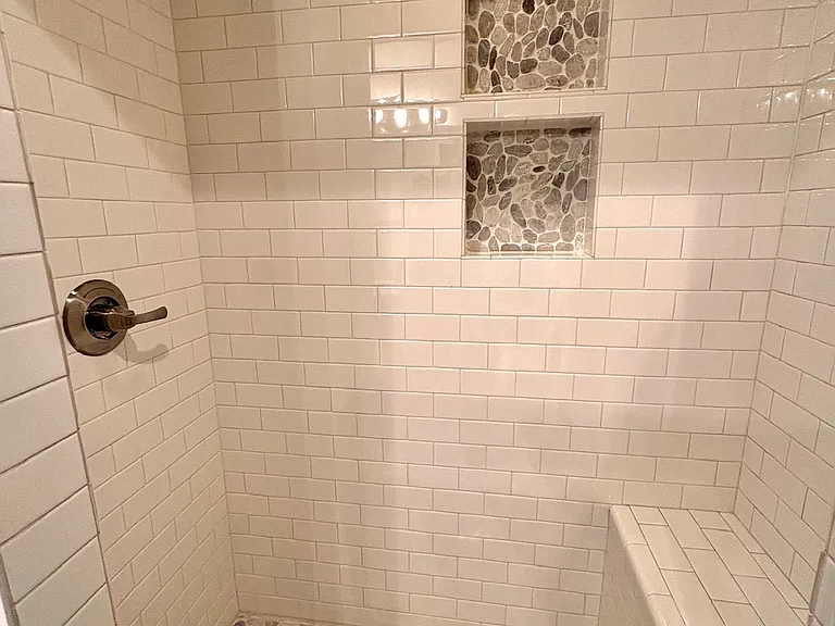 Spa shower with tiled bench and natural river stone accents.