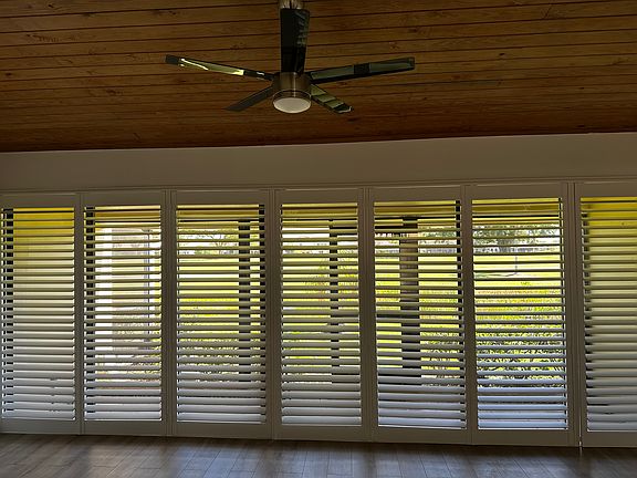 Expansive living room with new accordion shutters leading to rear screened in porch