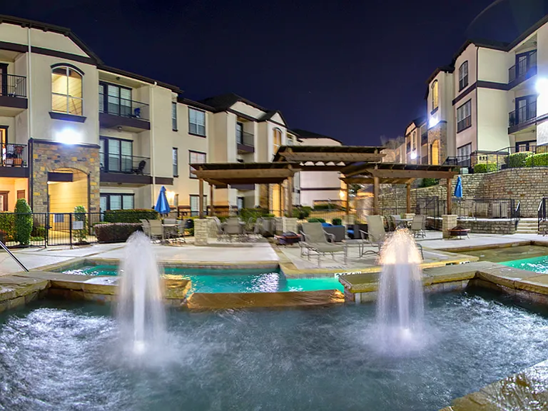 Resort-style swimming pool with fountain features and illuminated evening ambiance