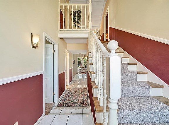 Hall into living area, and stairs to two upstairs bedrooms, bath and loft