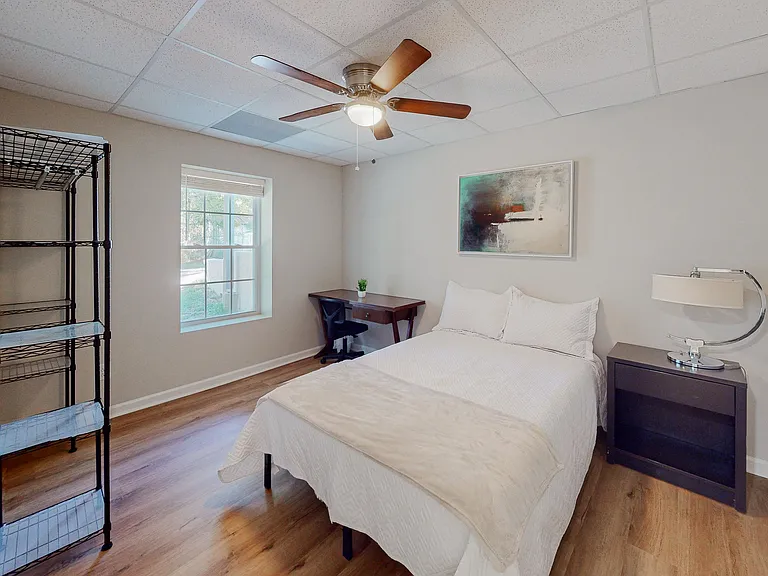 Bedroom complete with full sized bed, nightstand, desk, ceiling fan and clothes rack.