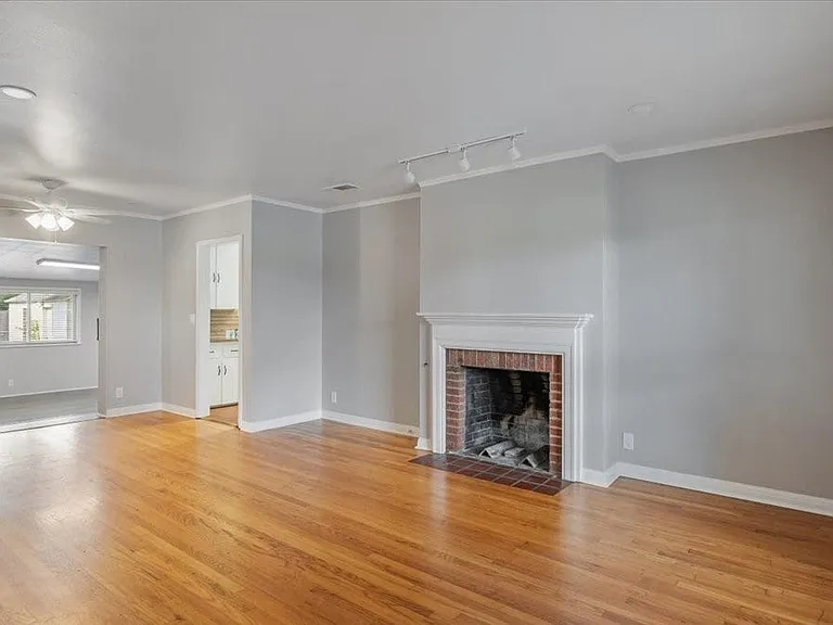 Spacious living/dining area with warm wood floors and a cozy wood-burning fireplace.