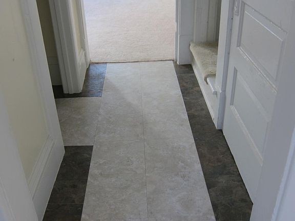 Tiled floors have a two-tone pattern at front entry, hallway