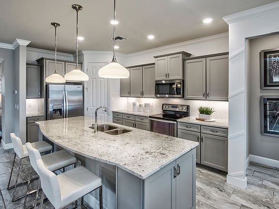 Well-appointed kitchen with quartz countertops, glass backsplash, and enlarged curved island, perfec