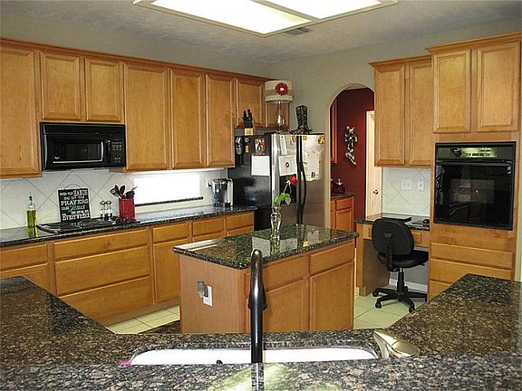 Gourmet island kitchen features granite counter tops, 42" cabinetry, black appliances and a spacious walk-in pantry