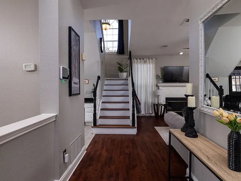 Modern open-plan living room with an elegant staircase and warm wood flooring.