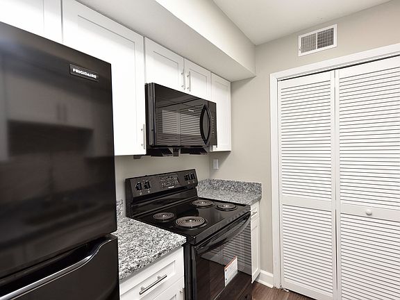 Kitchen with granite counters, modern cabinetry, and black appliances