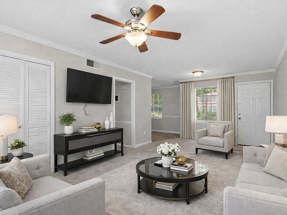 This expansive, beautifully staged living area offers plush carpeting, soft neutral colors, oversized windows, modern lighting, and an open, airy layout that feels warm, welcoming, and ideal for both everyday living and entertaining.