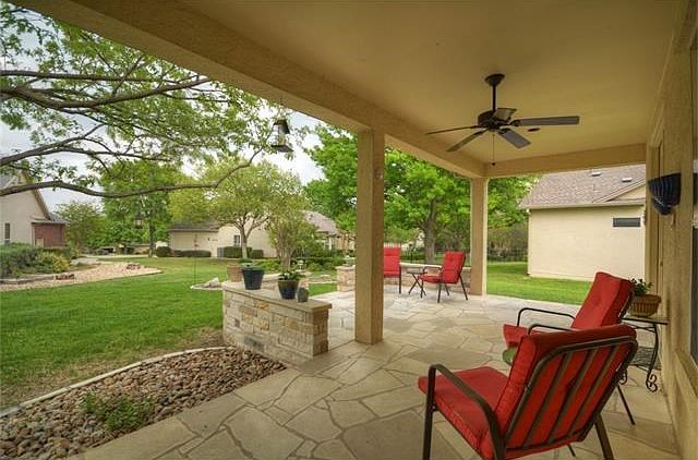 An Extended Covered Patio with stone Terrace views the wide lot abutting a neighboring cul-de-sac at this delightful Sun City Texas Trinity Premier home.