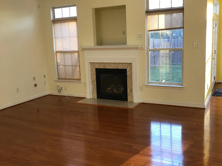 Living room with two south facing windows and gas powered fireplace.Wood flooring.