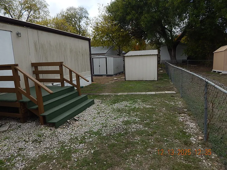 North side of home - showing deck to back door and 2 storage sheds to rear of photo.