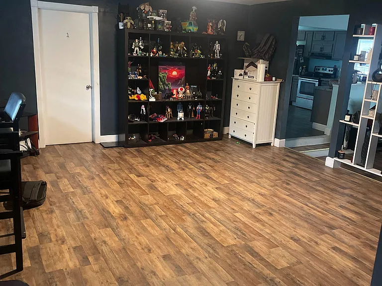 Spacious open living area with wood-look flooring and easy access to the kitchen, offering flexible space for seating or a de