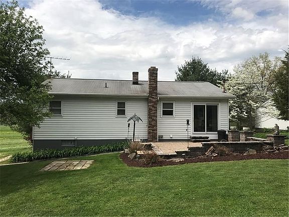 Rear view of house with stone patio and area for picnic table to the left.
