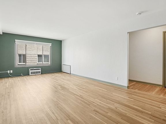 Bright, spacious living room with hardwood floors and a large window, offering abundant natural light in a modern apartment.