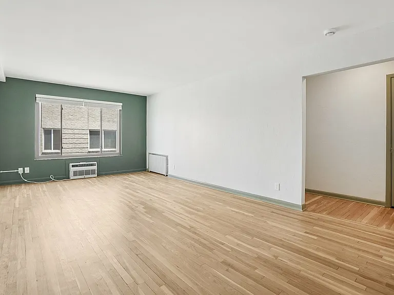 Bright, spacious living room with hardwood floors and a large window, offering abundant natural light in a modern apartment.