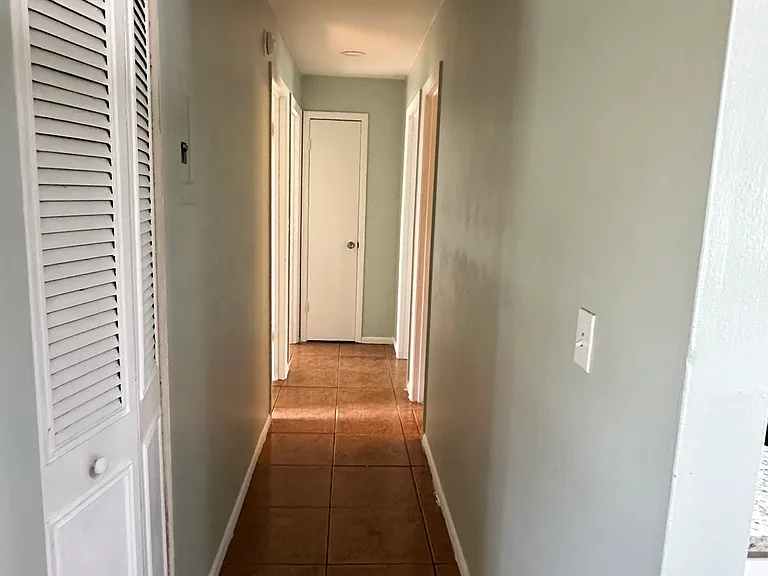 Hallway connecting rooms with linen closet at the end