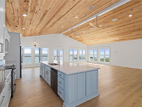Kitchen with appliances with stainless steel finishes, open floor plan, wooden ceiling, a kitchen island with sink, and light wood-style flooring