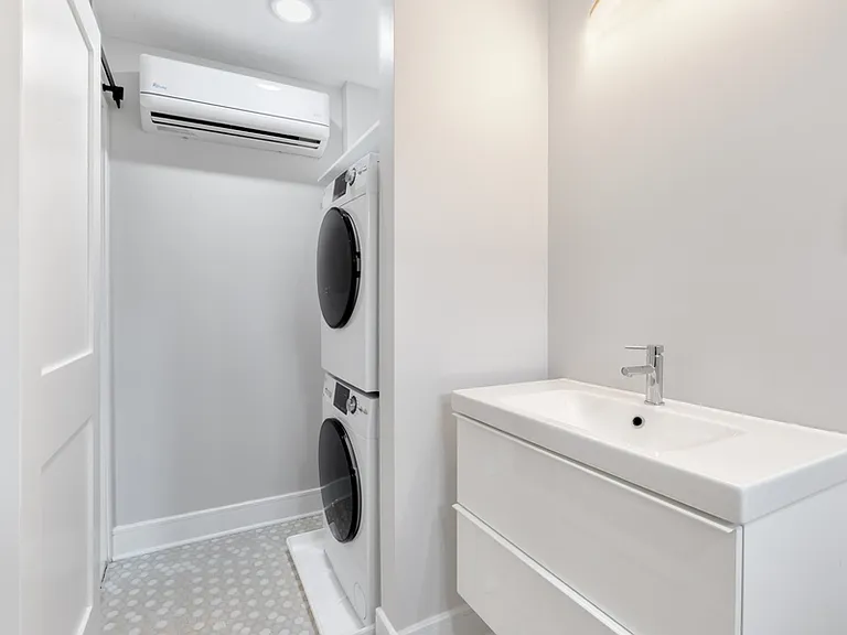 Full bathroom has tiled tub/shower, floating vanity, and stacked washer/dryer.