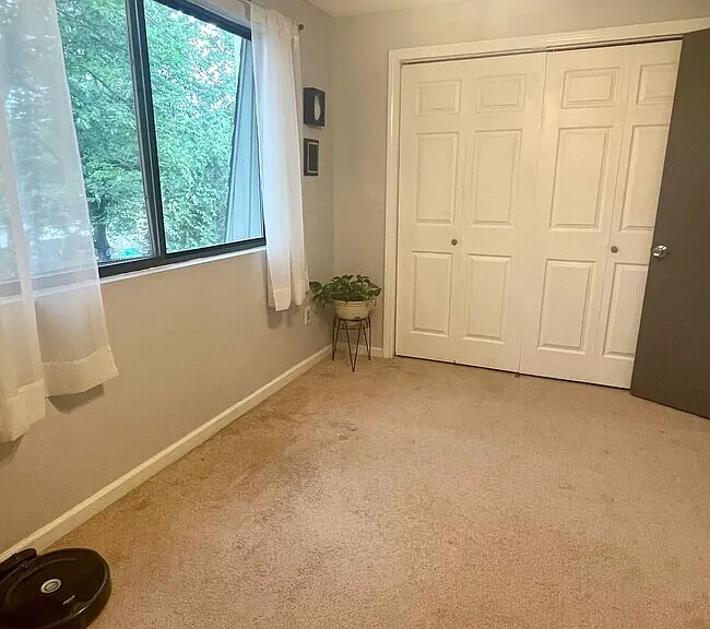 Alternative View: Second bedroom or office view with carpeted flooring, large window, and closet access.