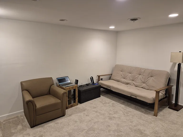 Flexible lounge setup with futon, workspace, and recessed lighting _ comfort meets utility.