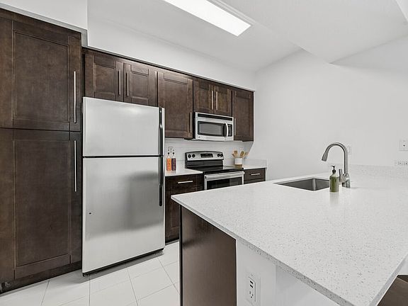 Renovated Package II kitchen with stainless steel appliances, tile backsplash, quartz countertops, and oak cabinetry (in most homes)