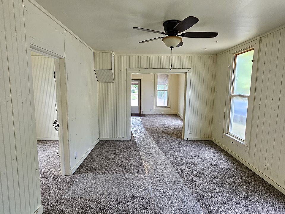 From kitchen doorway looking through dining room, to living room and front door. (Plastic runner is protecting new carpeting. Door on left of picture is middle bedroom.