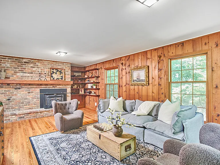 Family Room with pine floors and walls, looking through large windows into the woods.