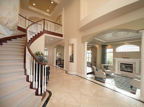 Elegant foyer with soaring ceiling, staircase with carpet and wood flooring, custom wall mural open to living room