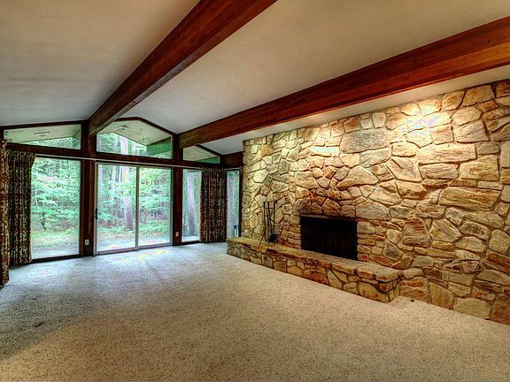 View of the sunken living room from the foyer is stunning with vaulted ceilings and stone fireplace spanning the entire room!  Full wall of windows/sliding door to the patio and  beautiful private setting.