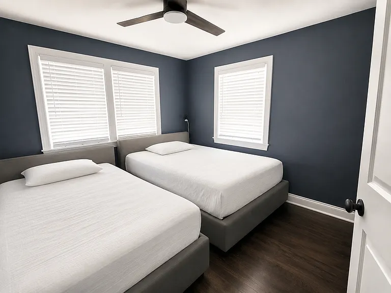 This spacious secondary bedroom offers expanded closet space, a modern ceiling fan with remote control, and abundant natural light for year-round comfort.