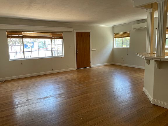 Large living room, lots of windows, looks onto front yard, open design with kitchen and dining room.