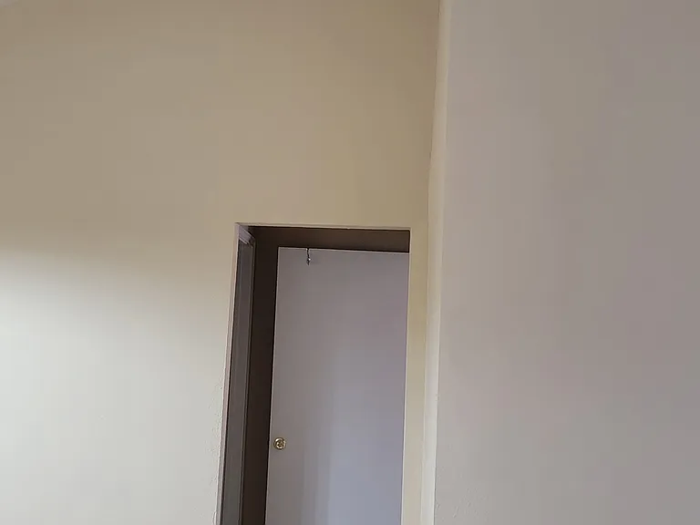 Living room with tall high ceiling and view to 2nd bedroom entrance