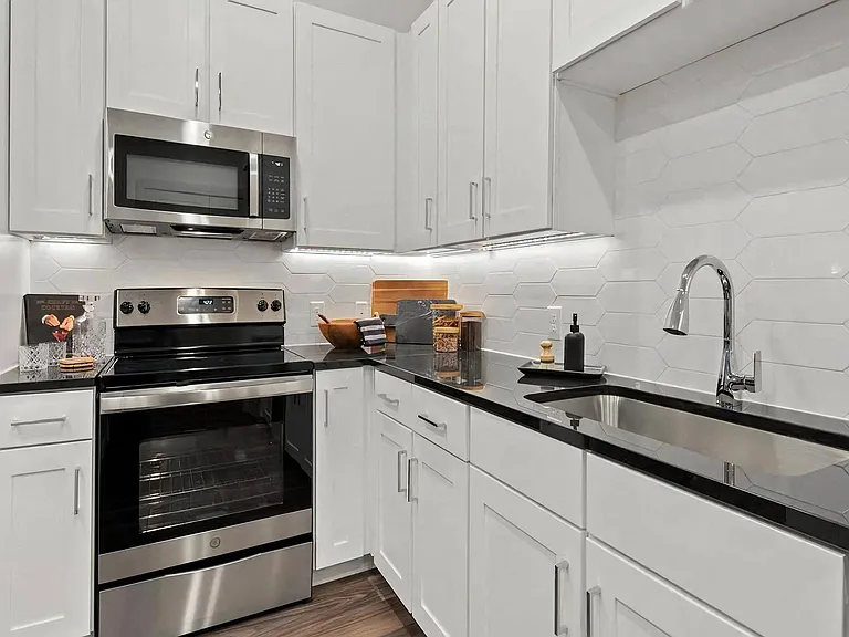 White Cabinet Kitchen with Hexagon Tile Backsplash and Black Counters