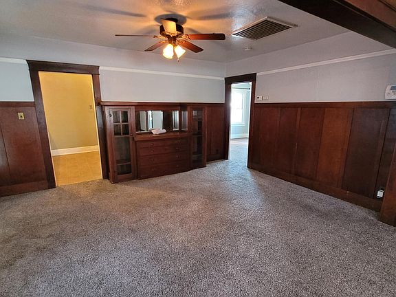 Dining room with vintage wood paneling and built-in buffet cabinet. Door to kitchen on left, door to bedroom 2 on right
