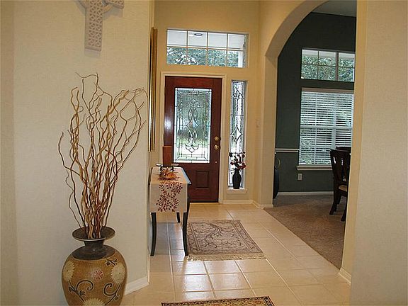 View of the front entrance showcases the beautiful glass door and arched entry way leading to the formal dining room.