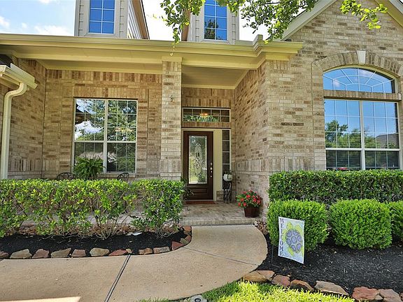 Delightful sitting and rocking front brick porch, arched brick windows and moss rock flowerbeds.