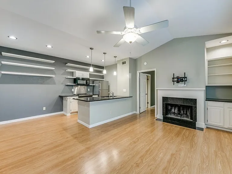 Kitchen with lofted ceiling, pendant lighting, white cabinetry, light hardwood / wood-style floors, and stainless steel refrigerator.