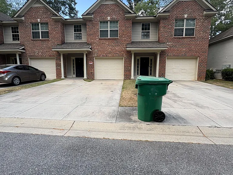 Brick townhome-style exterior with attached garage, private driveway parking, and a covered front entry.