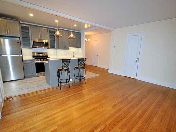 Renovated Kitchen with center Island, pendent lighting, Granite Counters, Stainless Steel Appliance including a dishwasher, range, microwave and refrigerator. The wall separating the eat-in-kitchen and living room have been removed and a center Island ins