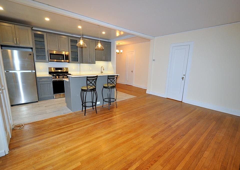 Renovated Kitchen with center Island, pendent lighting, Granite Counters, Stainless Steel Appliance including a dishwasher, range, microwave and refrigerator. The wall separating the eat-in-kitchen and living room have been removed and a center Island ins