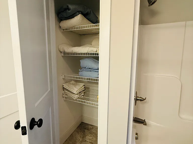 Secondary bathroom linen closet with linens.
