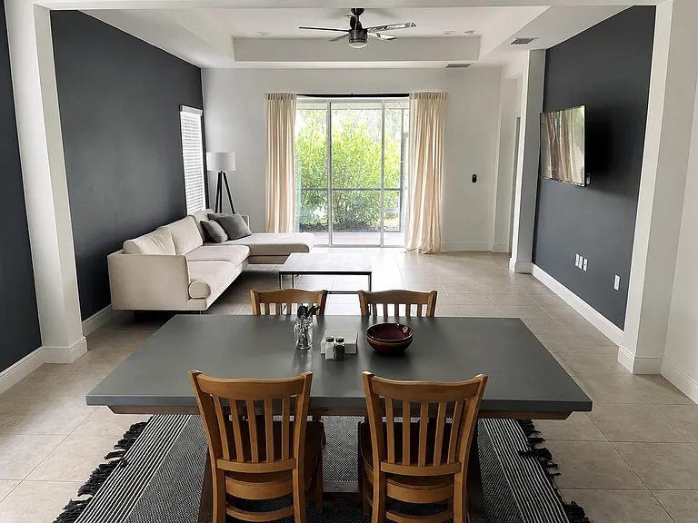Open-concept living and dining area with a ceiling fan, tiled floors, and sliding glass doors to the patio.