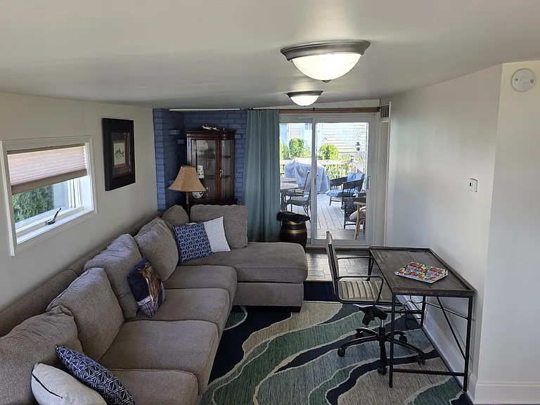 Family room or work space with a desk that has buil-in USB and power. Sliding glass doors lead to large deck.